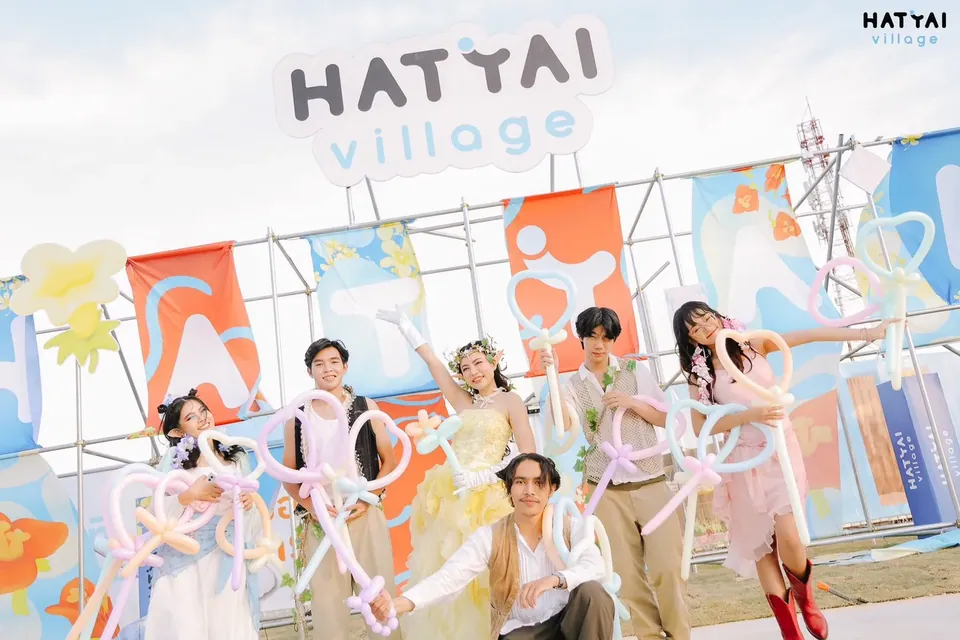 ทีมนักแสดงถือลูกโป่งดัดถ่ายภาพหน้าฉากงานกลางแจ้ง