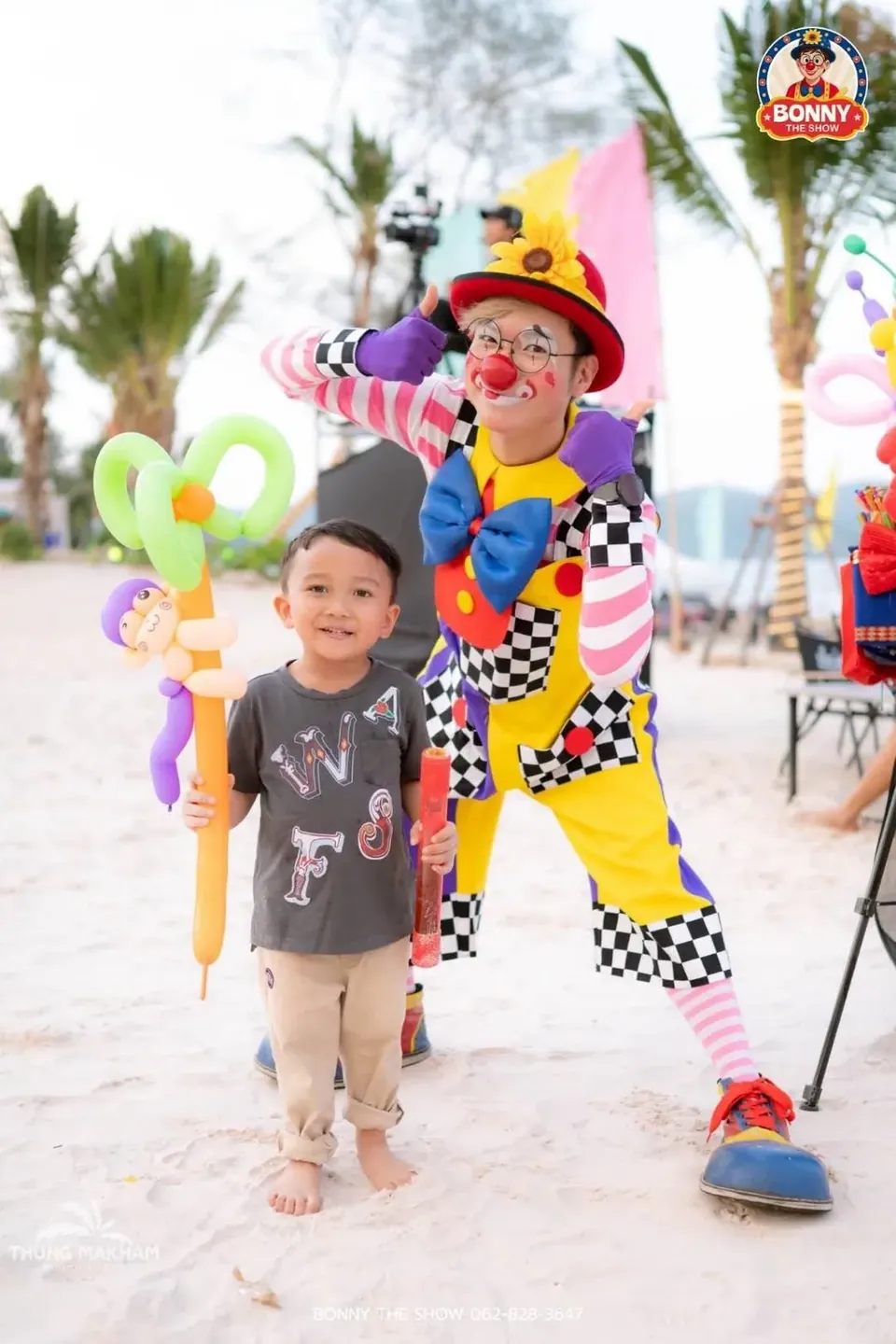 ตัวตลกโบโซ่พร้อมลูกโป่งดัดยืนถ่ายภาพกับเด็กชาย