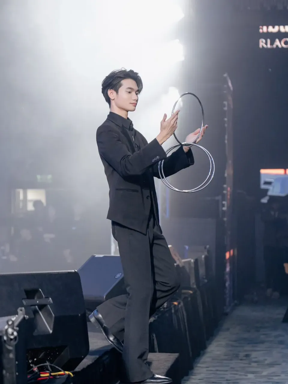 นักมายากลแสดงมายากลห่วงบนเวทีในม่านควัน