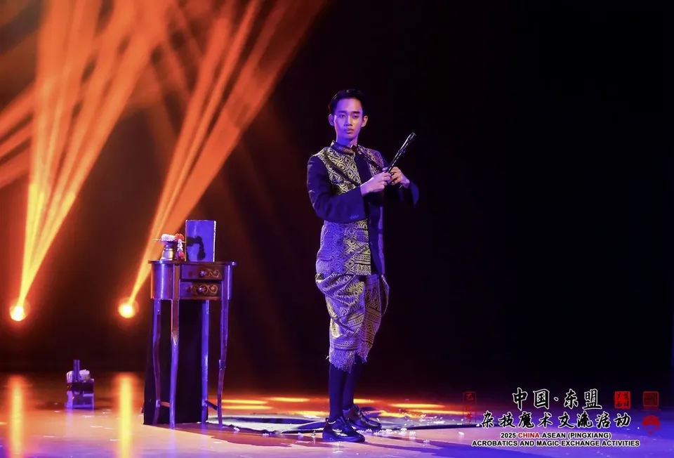 นักมายากลในชุดลายบนเวทีการแสดงพร้อมลำแสงสีส้ม