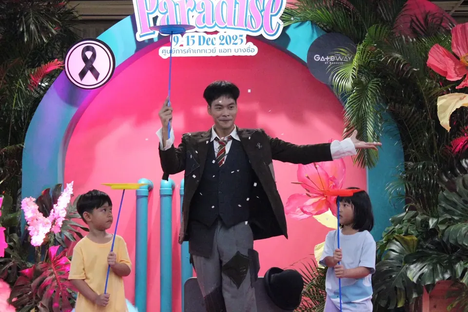 นักมายากลแสดงบนเวทีสีชมพูในงานเด็ก พร้อมอาสาสมัครสองคน
