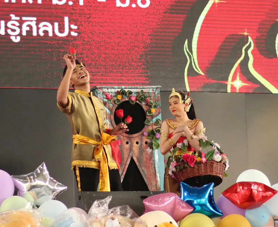 นักแสดงโยนไพ่บนเวทีงานวัฒนธรรมที่ตกแต่งด้วยลูกโป่ง
