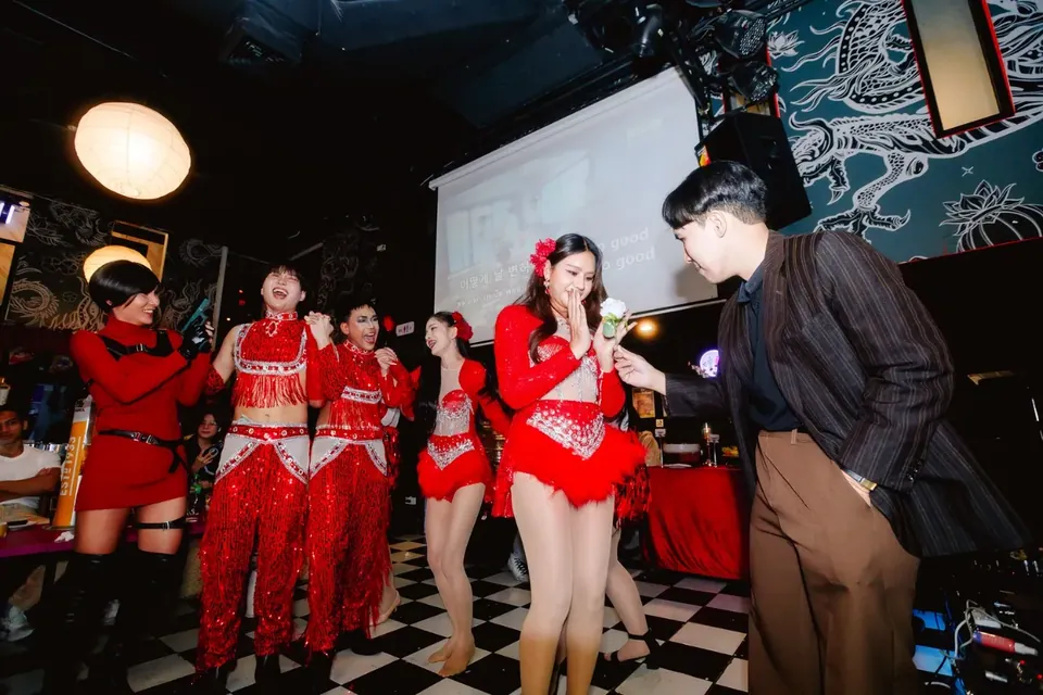 นักมายากลแสดงบนเวทีร่วมกับทีมนักเต้นชุดแดง